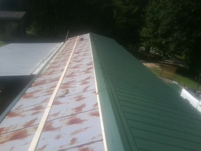 Old rusted panels beside newly installed green metal roofing — Wind Damage Roof Repair by Roofing Brothers in Ravenel