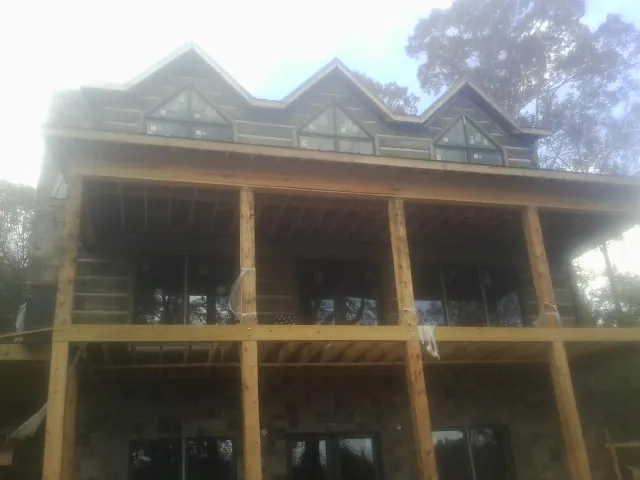 Dormers and porch framing on a large log home under construction — Roof Coating work by our crew in Ravenel