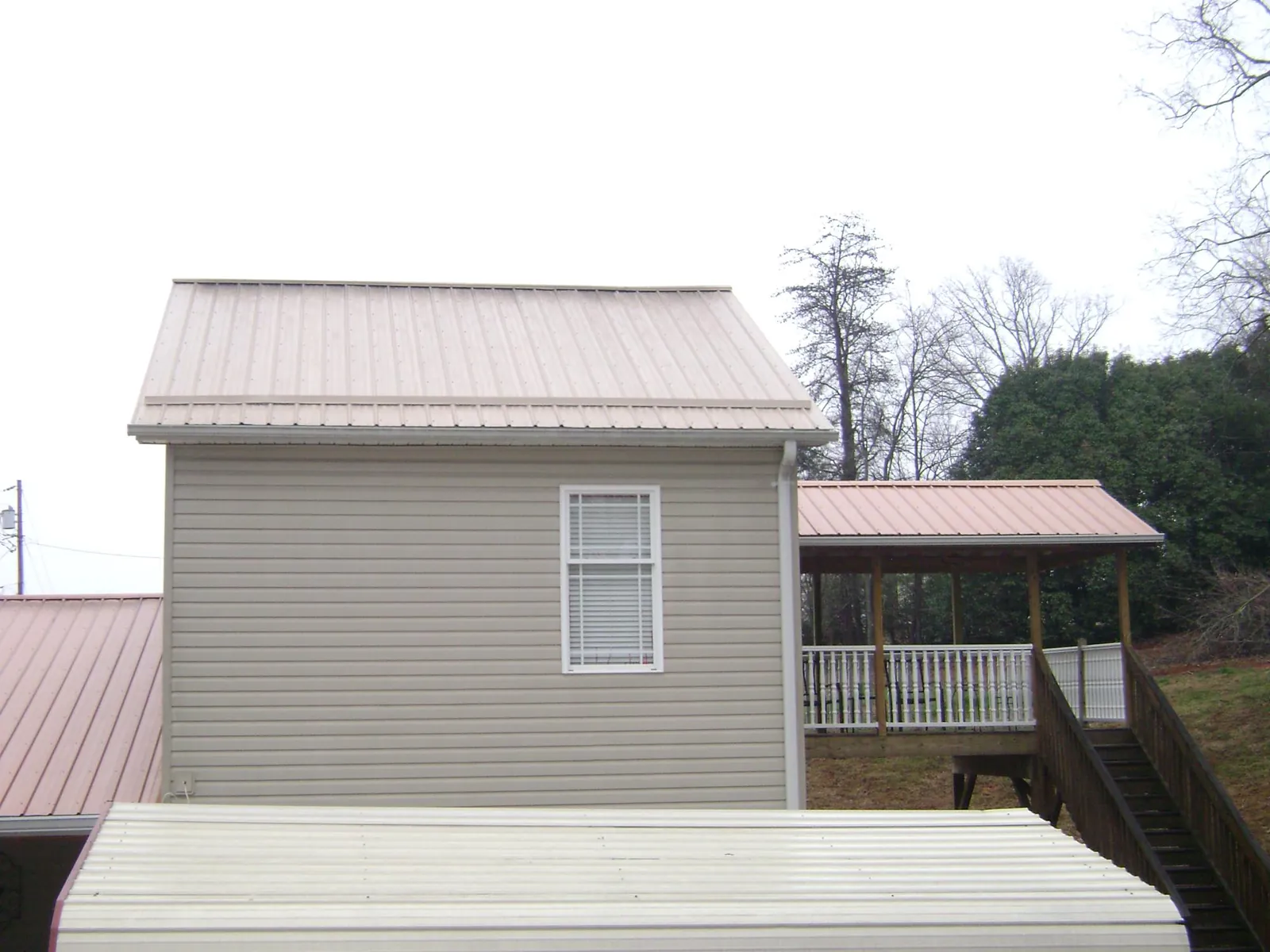 Tan metal roofs on a two story addition and attached porch, from a Roof Replacement job in Ravenel