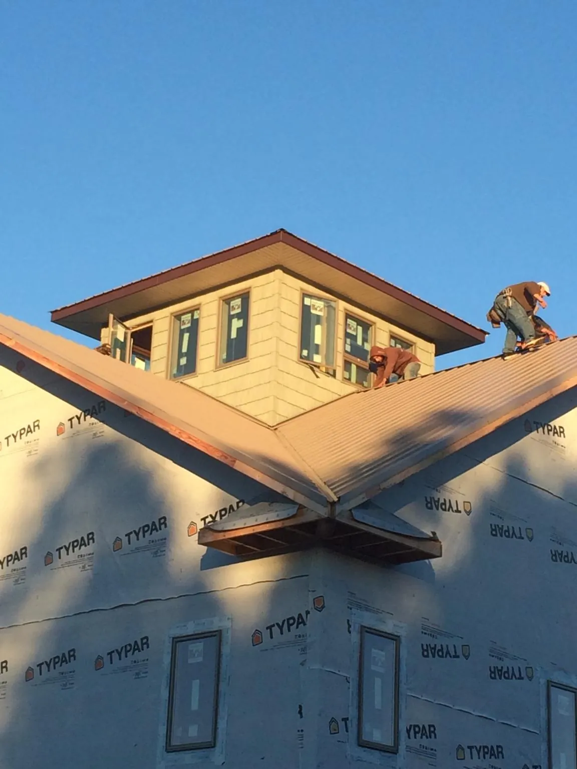 Roofers working around a rooftop cupola on a new metal roof at sunset — Roof Waterproofing in Ravenel by Roofing Brothers